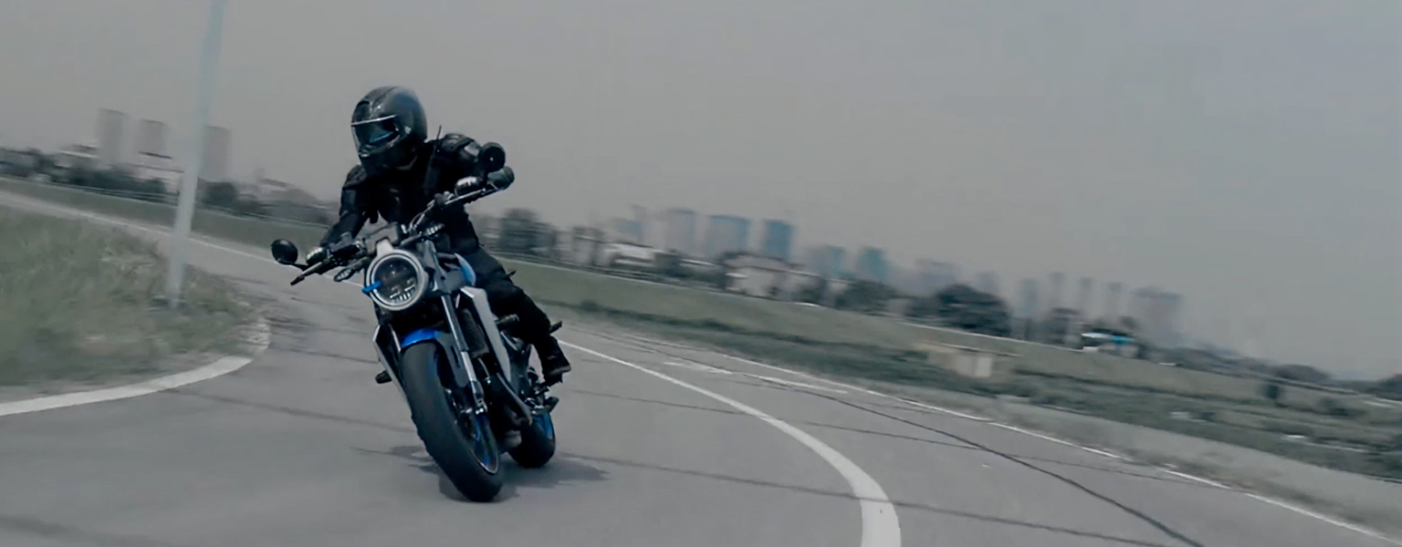 Zontes motos en Uruguay - Zontes 350GK azul y negra inclinando en una curva con faro redondo y una postura de manejo firme.
