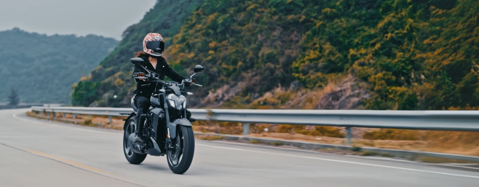 Zontes motos en Uruguay - Zontes 350V gris siguiendo una curva de ruta junto a la ladera, con piloto equipado para carretera.
