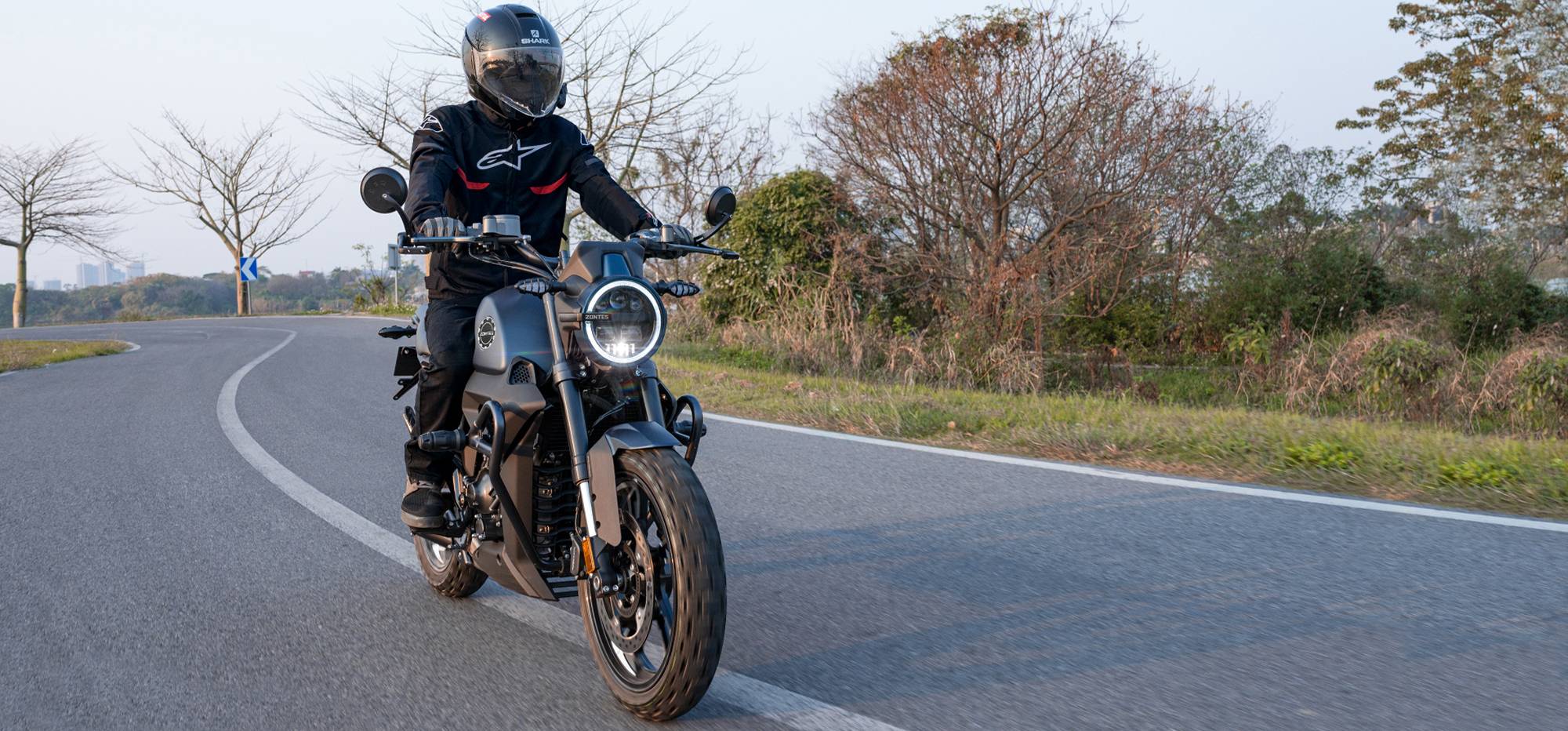 Zontes motos en Uruguay - Moto Zontes 200G rodando en una curva con piloto de casco integral y faro encendido. Zontes motos en Uruguay - Zontes 200G en movimiento con conductor equipado sobre una curva asfaltada.
