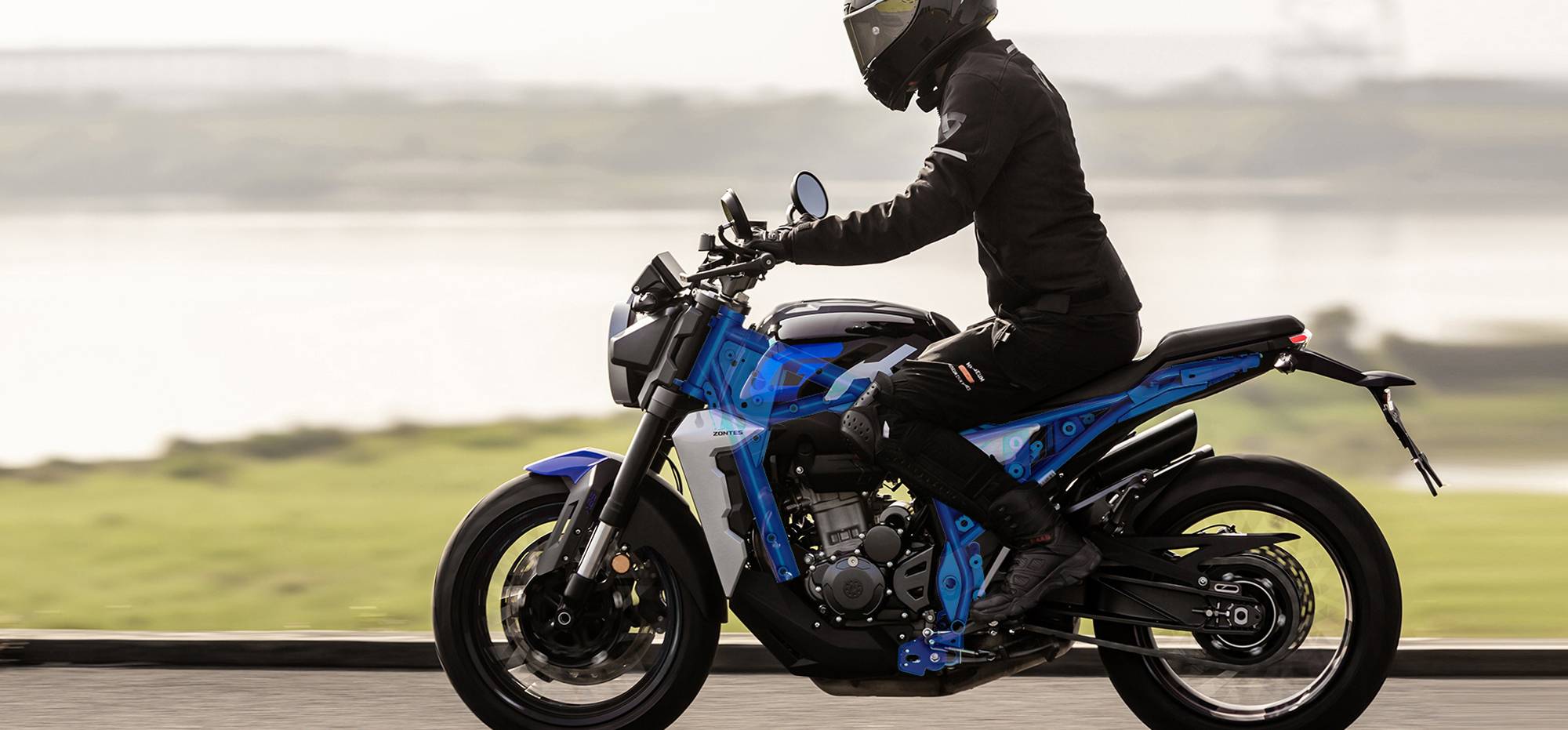 Zontes motos en Uruguay - Moto Zontes 350GK rodando con piloto de casco integral en una escena exterior abierta. Zontes motos en Uruguay - Zontes 350GK en movimiento con conductor equipado sobre un camino junto al agua.