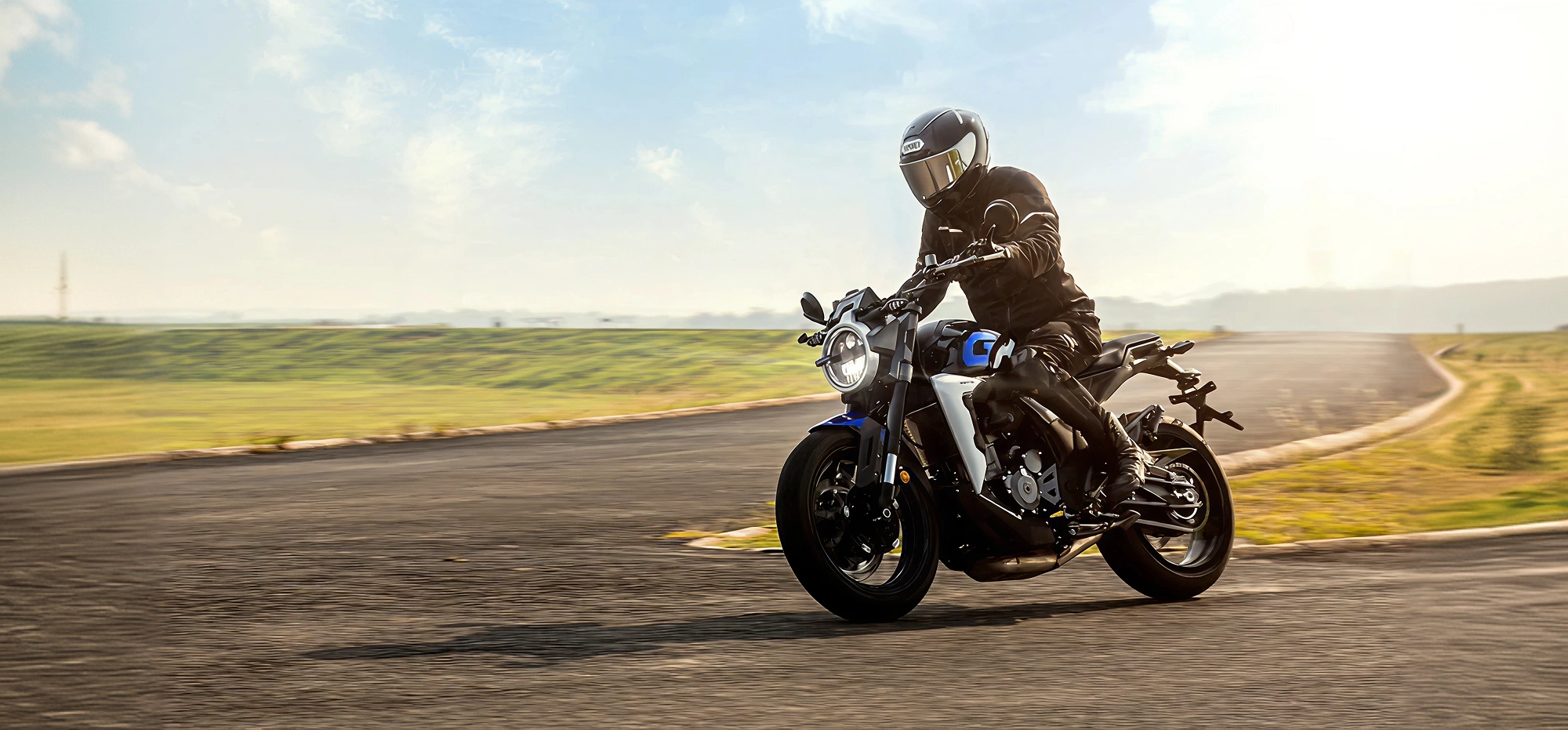 Zontes motos en Uruguay - Moto Zontes 350GK circulando con piloto de casco integral en una escena abierta y luminosa. Zontes motos en Uruguay - Zontes 350GK en marcha sobre asfalto con conductor equipado y luz cálida de día.