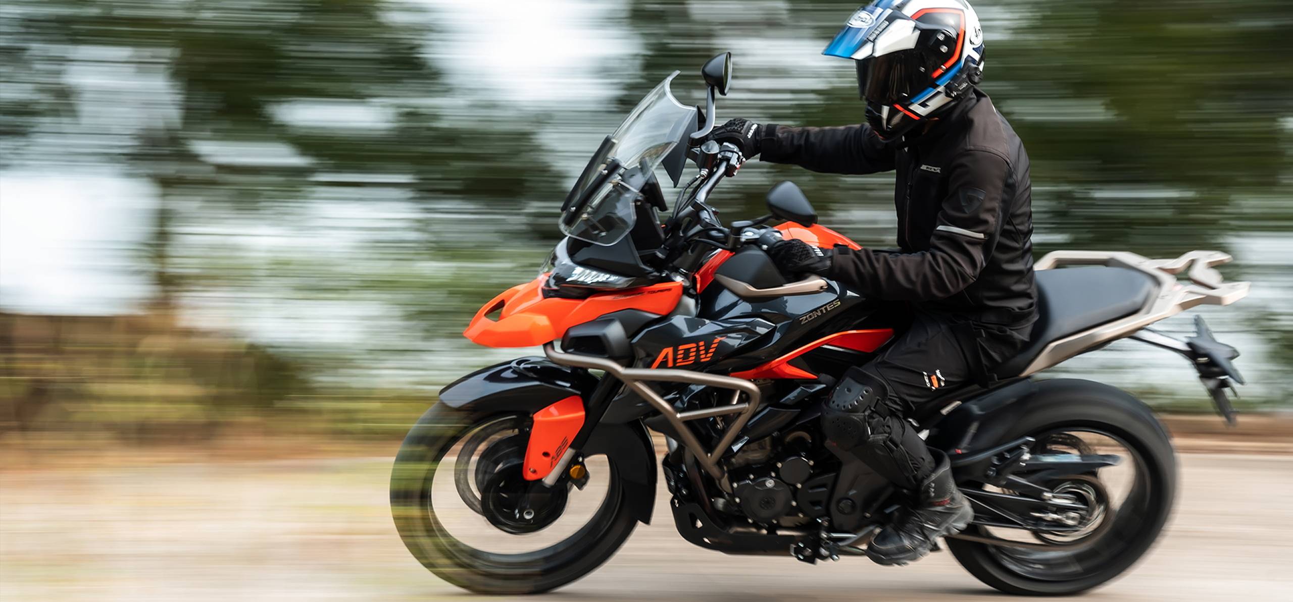Zontes motos en Uruguay - Piloto sobre Zontes 350T naranja y negra en movimiento lateral derecho, con fondo barrido y sensación de velocidad.