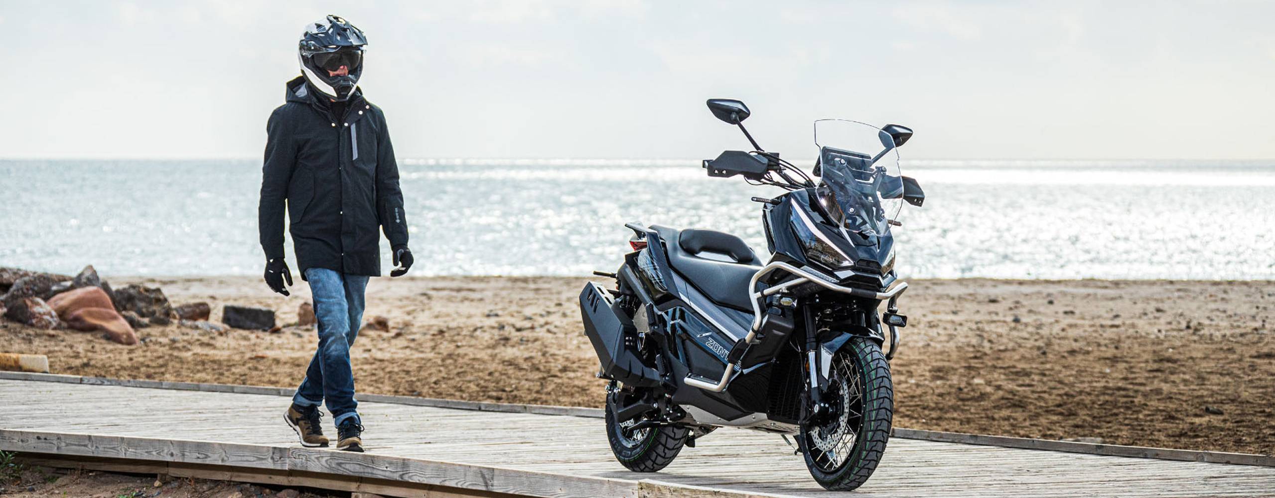 Zontes motos en Uruguay - Zontes 368G junto al mar con una silueta robusta, lineas adventure y un conjunto pensado para recorrer. Zontes motos en Uruguay - Zontes 368G gris estacionada junto a la costa con defensas delanteras, parabrisas alto y una postura de gran porte.