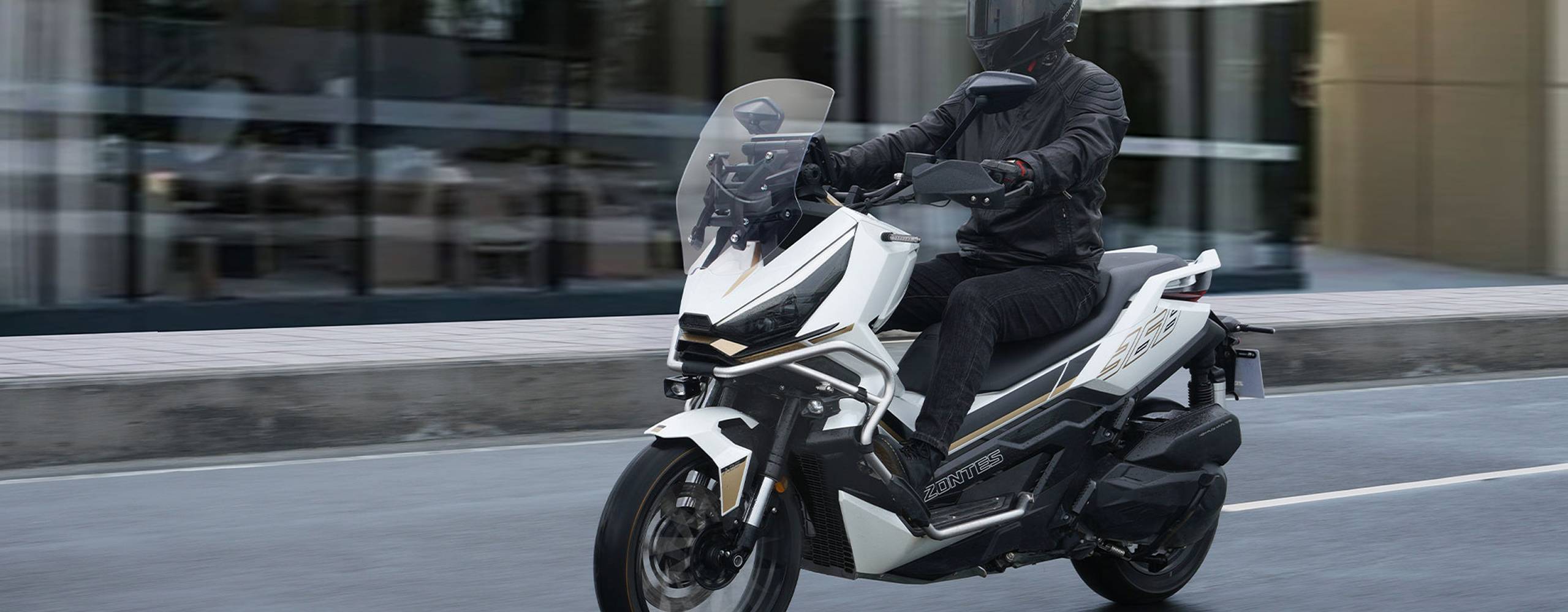 Zontes motos en Uruguay - Zontes 368G recorriendo una avenida urbana con lineas marcadas, gran porte y una imagen contemporanea. Zontes motos en Uruguay - Zontes 368G blanca en marcha por la ciudad con parabrisas alto, defensas delanteras y una postura comoda de conduccion.