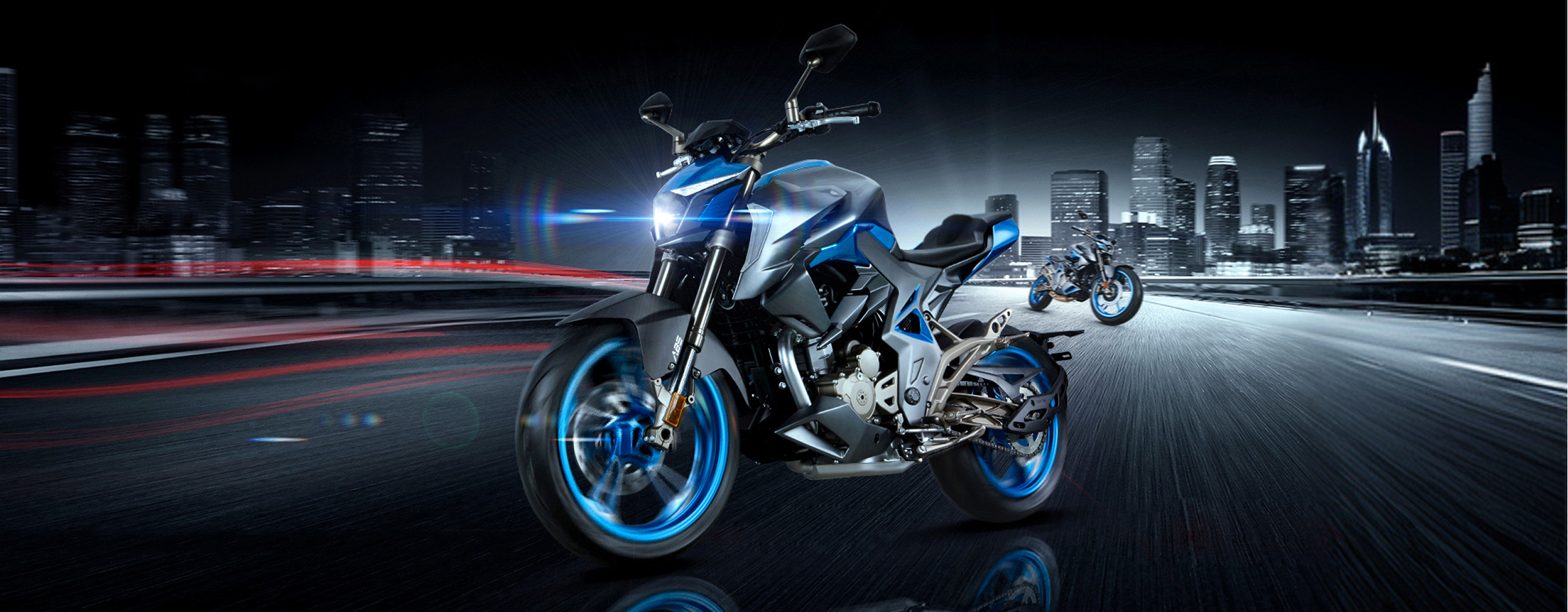 Zontes motos en Uruguay - Zontes 310R azul y negra en movimiento nocturno con faro encendido y otra moto al fondo.