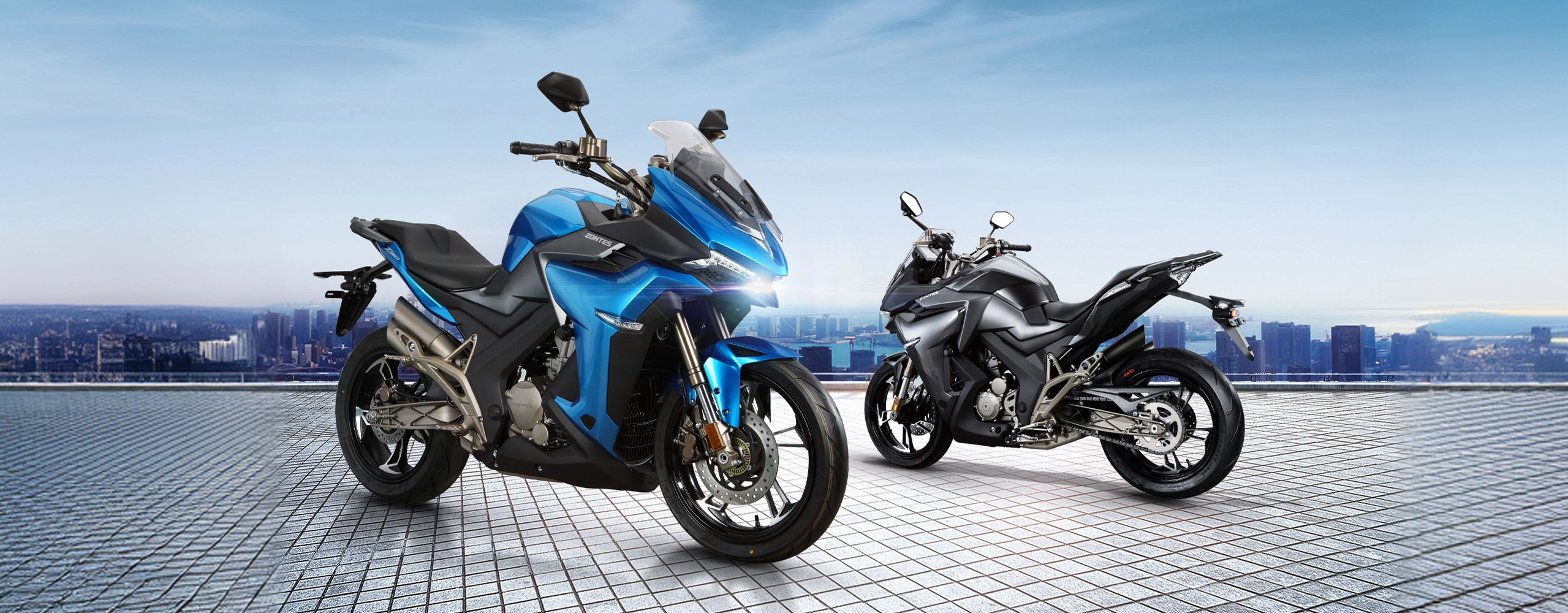 Zontes motos en Uruguay - Dos motos Zontes 310X, una azul y una gris oscura, ubicadas sobre una explanada con ciudad al fondo.