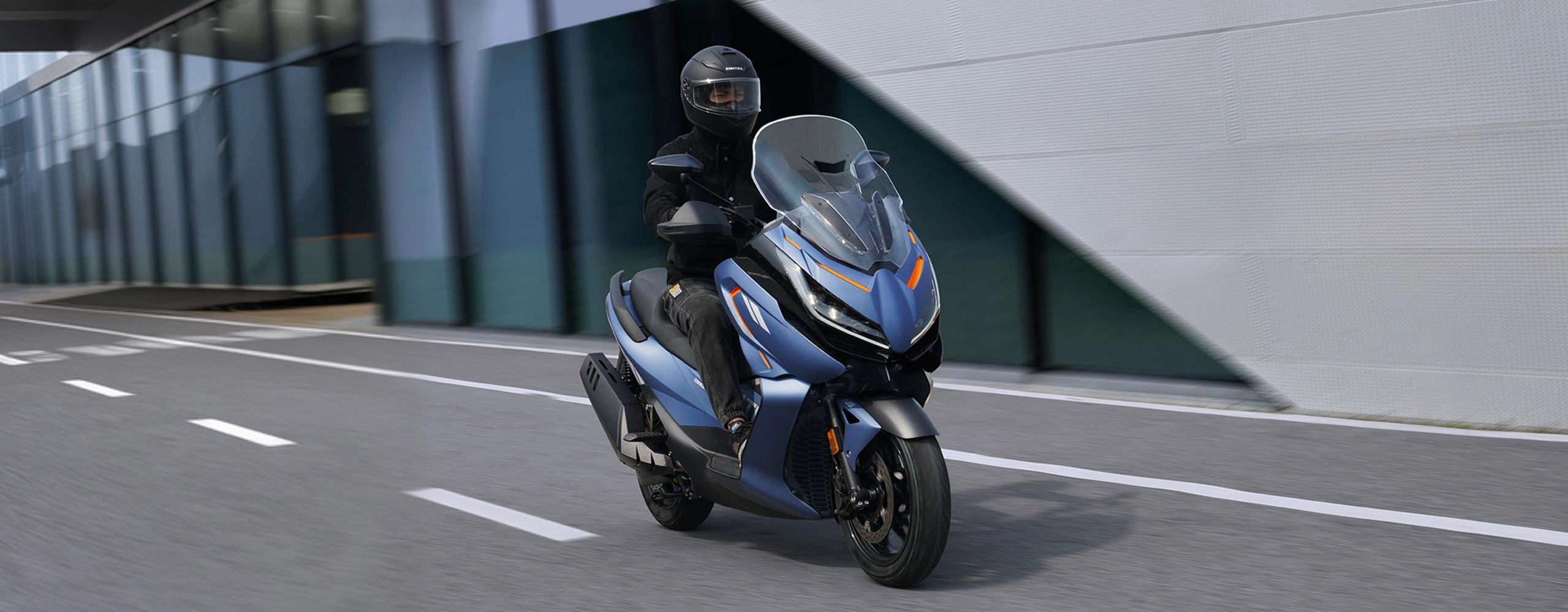 Zontes motos en Uruguay - Scooter 368E azul en marcha con iluminacion delantera integrada y proteccion aerodinamica elevada. Zontes motos en Uruguay - Zontes 368E azul avanzando por calle urbana con conductor y frente carenado de gran parabrisas.