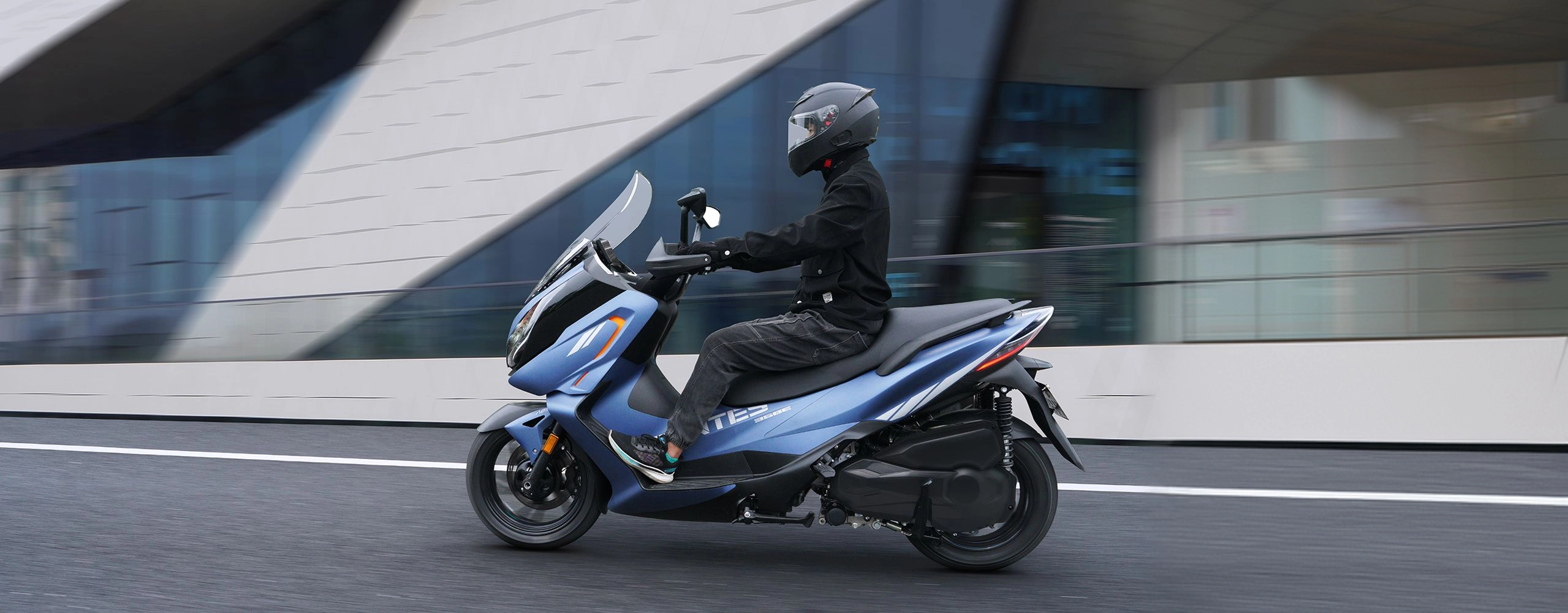 Zontes motos en Uruguay - Zontes 368E azul en ciudad con asiento amplio, parabrisas elevado y carroceria de trazos fluidos. Zontes motos en Uruguay - Scooter Zontes 368E azul con conductor recorriendo una avenida y mostrando su perfil lateral.