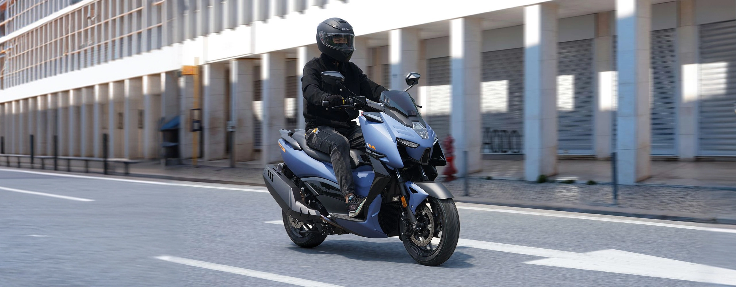 Zontes motos en Uruguay - Scooter 368M azul en ciudad con conductor, faro central y lineas angulosas en el carenado. Zontes motos en Uruguay - Zontes 368M azul avanzando por una avenida con conductor y frente del scooter visible.